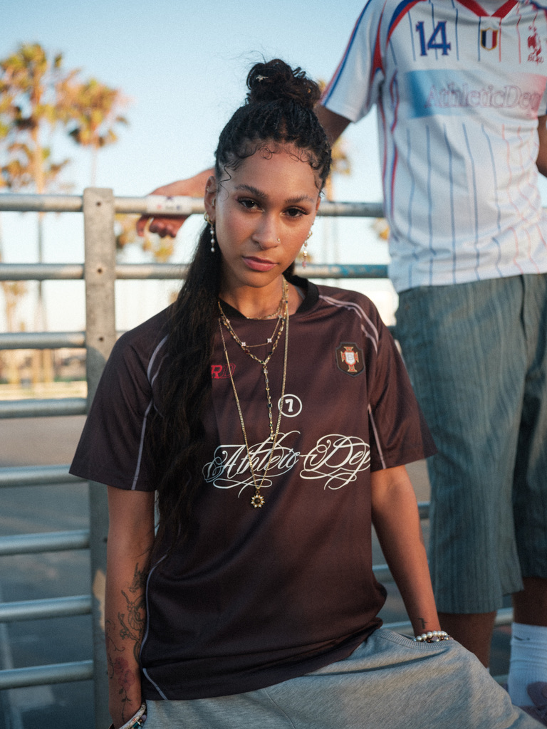 Maria Williams in a brown BLRD soccer jersey leaning on a railing