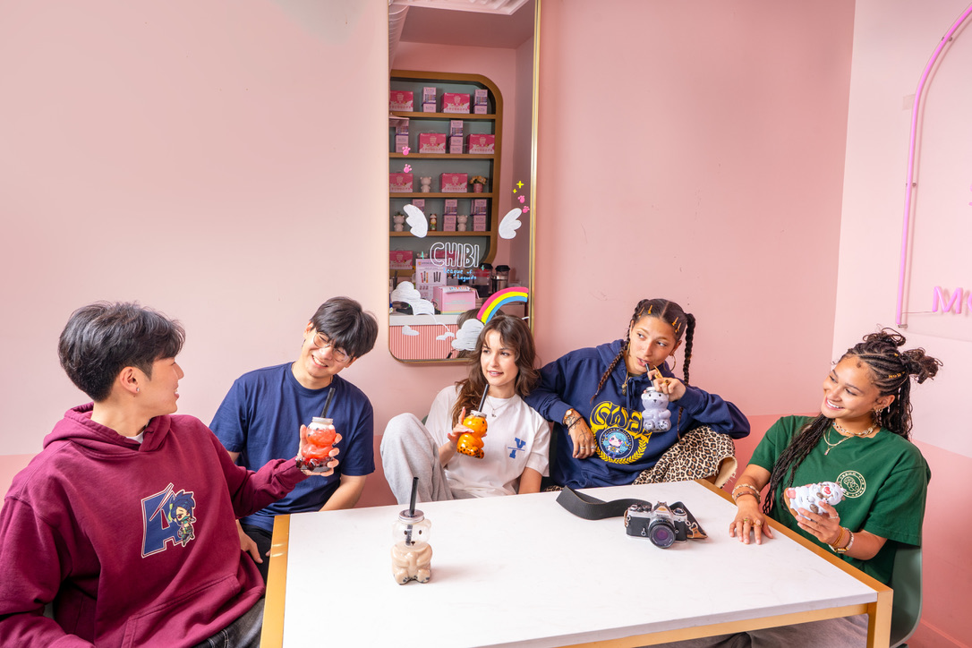 Maria Williams and friends in League of Legends hoodies and tees sharing drinks at the Chibi café